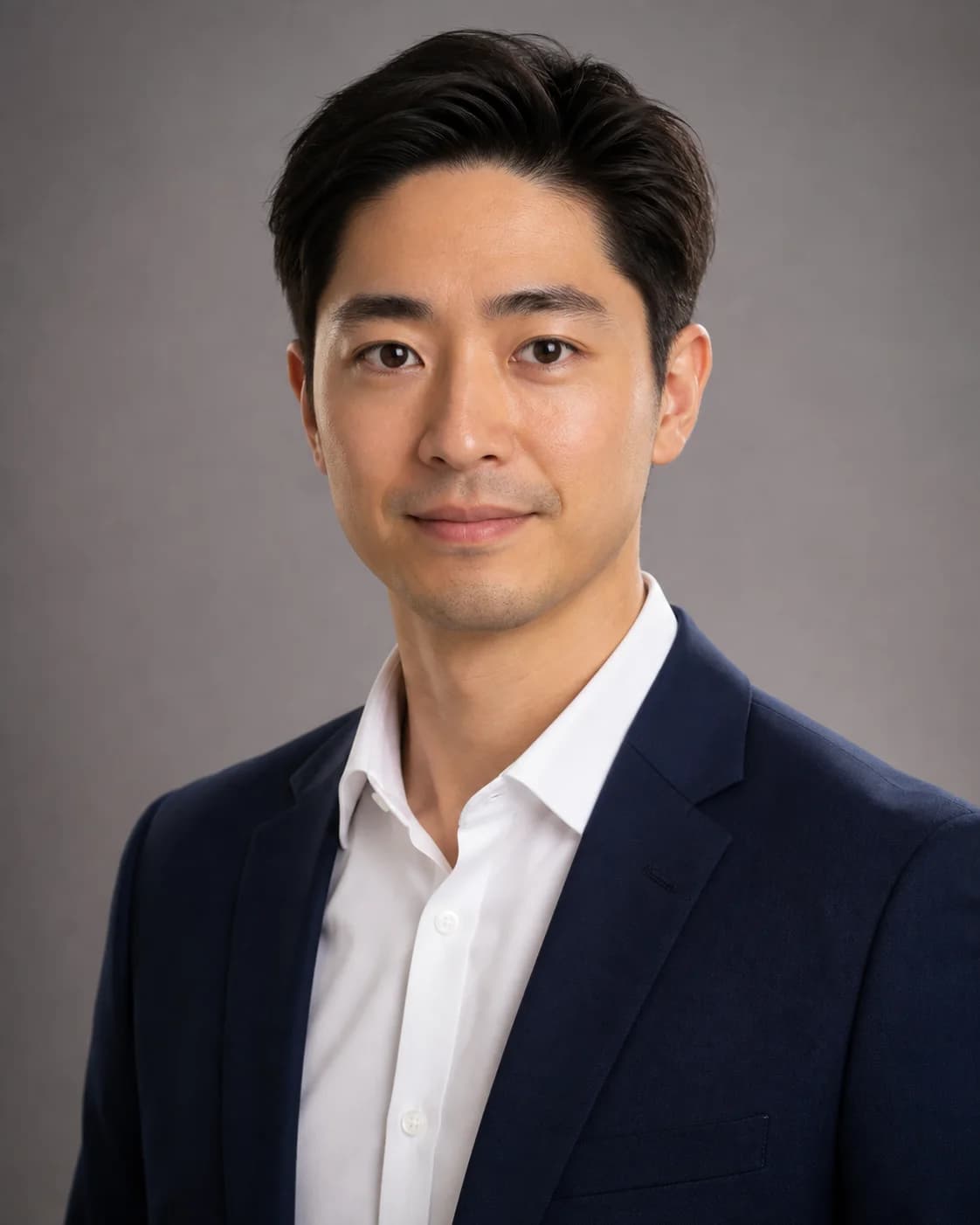 A professional corporate headshot of a fictional adult East Asian man in his early 30s wearing a navy blazer and crisp white 